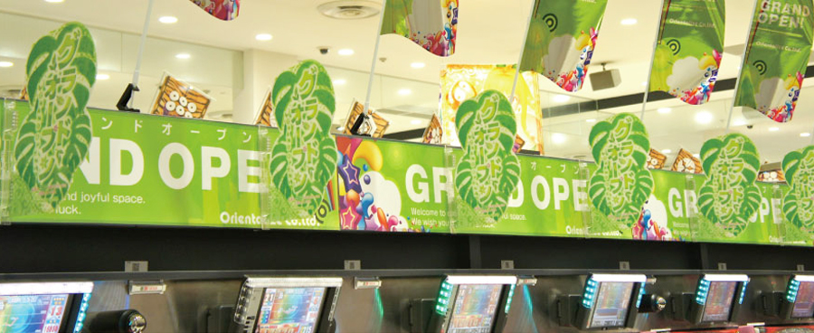 エコキャッチャー69　ホール店内設置イメージ：幕板装飾のプレートPOP・フラッグPOP取付けキャッチ。エコ。安全。優しい。幕板カバー率90％以上。マグネットで安心の装飾を。両サイドのリリースボタンで取付け取外しが更に楽に！　永久磁石のホールドカは弱まることがなく長期間ご使用いただけます。＊画像はマグネットタイプです。【パチンコPOP取付け部材キャッチ・店内装飾部材・装飾備品で、ホール運営合理化・コスト削減・エコ　オリエンタライズ】